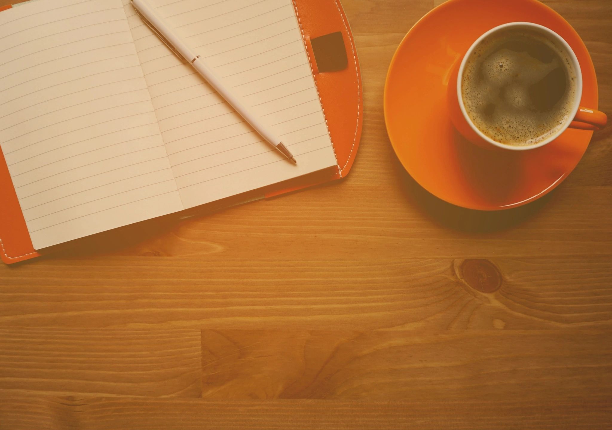 Coffee, notebook, pen on wooden desk
